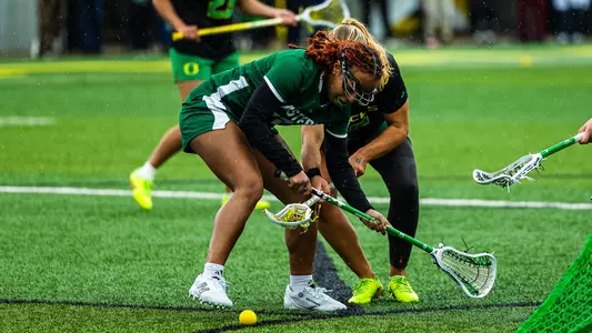 Marley Helton works for a ground ball near the Eastern Michigan crease against an attacking Oregon player