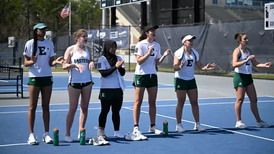 Players from the Eastern Michigan tennis team line the court and cheer on a teammate in the final match at North Florida