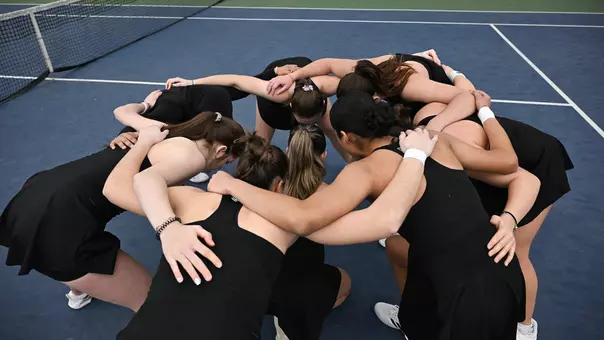The 2025-26 tennis team huddles on the court at the Chippewa Club before playing its match against visiting Oakland