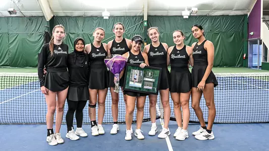 Senior Regina Mendez Carreno (center) stands at center court holding flowers and framed photos of herself while being flanked by her teammates as the celebrate her Senior Day