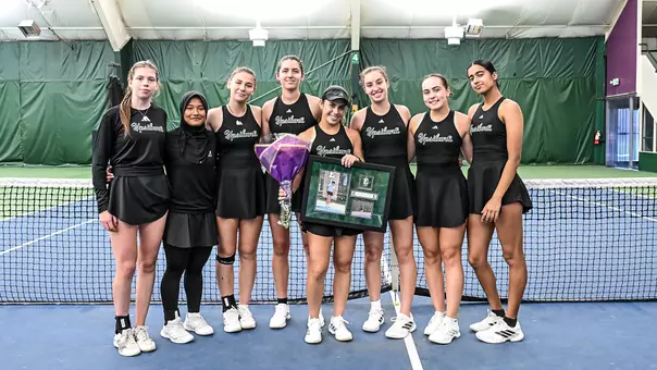 Senior Regina Mendez Carreno (center) stands at center court holding flowers and framed photos of herself while being flanked by her teammates as the celebrate her Senior Day