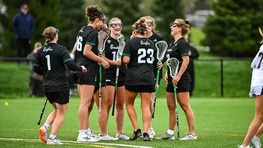 Members of the lacrosse team smile as they huddle up near the eight meter circle after scoring a goal against Robert Morris