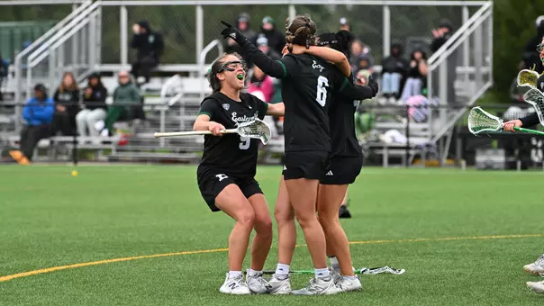 Members of the lacrosse team huddle and celebrate a goal late in the game with Robert Morris