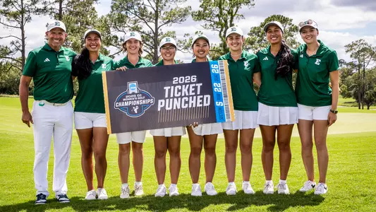 The women's golf team (L-R), including Head Coach Josh Brewer, Jasmine Leovao, Savannah de Bock, Erina Tan, Baiyok Sukterm, Mariana Vega, Jasmine Leovao, and Assistant Coach Caterina Don, poses with the NCAA Ticket Punched board after earning a berth into the NCAA Championships
