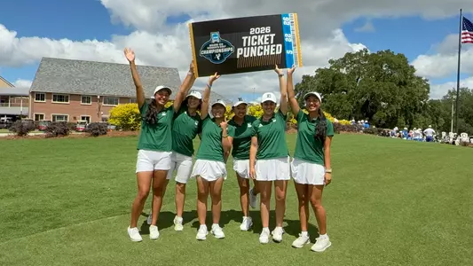 The women's golf team holds up a ticket saying they have punched their ticket to the NCAA Championships for the first time in program history