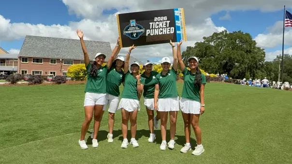 The women's golf team holds up a ticket saying they have punched their ticket to the NCAA Championships for the first time in program history