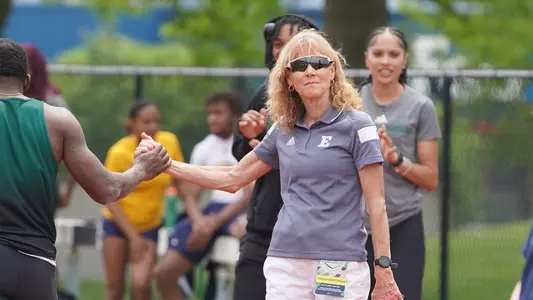 Sue Parks high fives student athlete at 2023 Outdoor MAC Championships