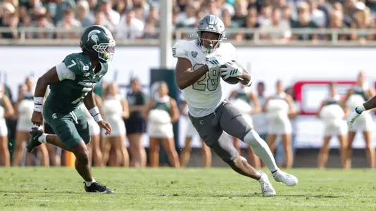 Braydon Bennett (28) cuts back against a Michigan State defender inside Spartan Stadium