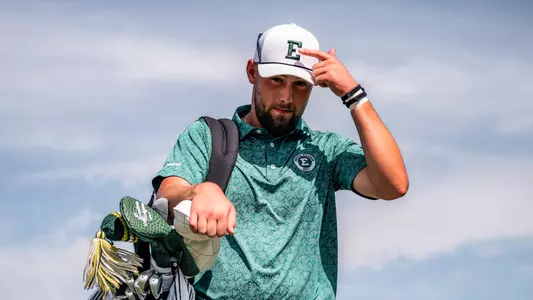 Charlie Box points to the Block E logo on his hat while carrying his back on Whirlwind Golf Course in Chandler, Ariz.