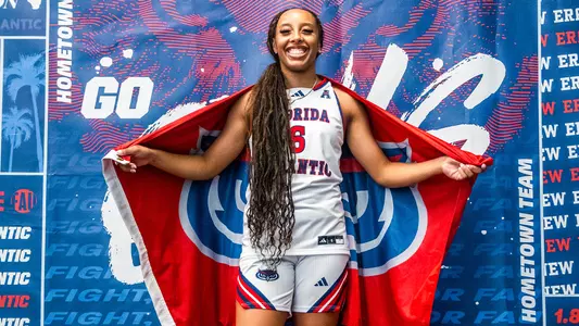 Jazzy Gipson - WBB Guard smiling and holding a Florida Atlantic flag behind her