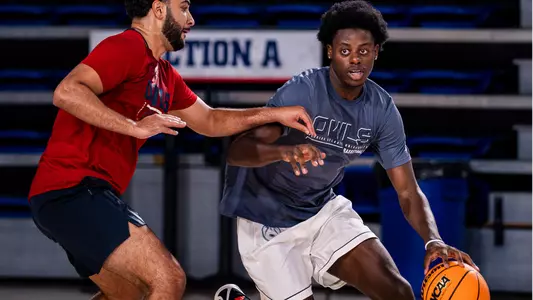 Franck Belibi Jr. dribbling at practice with Assistant Coach Demond Parker