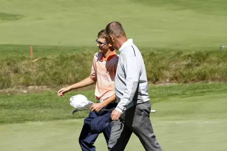 Head coach Mike Small walks off the 18th green with Dylan Meyer.