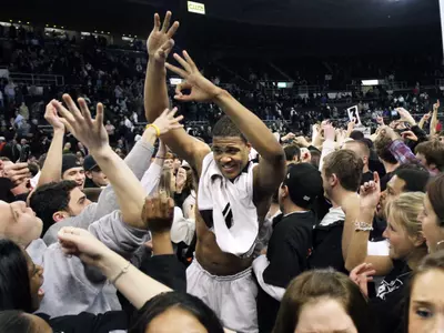 Providence's Bilal Dixon, center, celebrates with fans who stormed the court after Providence's 81-66 upset victory over Connecticut in an NCAA college basketball game in Providence, R.I., Wednesday, Jan. 27, 2010. (AP Photo/Elise Amendola