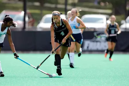 Field Hockey forward Izzy Mendez dribbles up field while a Columbia defender jabs at the ball during their matchup at Lennon Family Field.