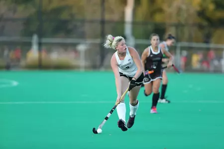 Field Hockey defender Abby Thornton has possession of the ball while she looks up and scans the field during gameplay.