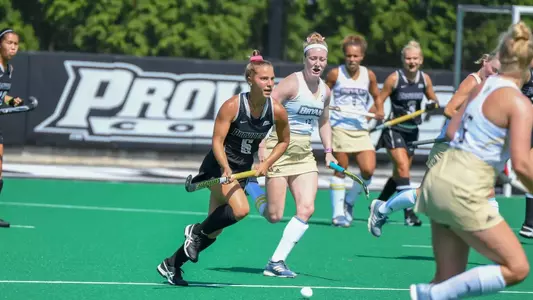 Field Hockey forward Kari Moyer dribbles the ball upfield while a Bryant defender trails behind her during their matchup at Lennon Family Field.