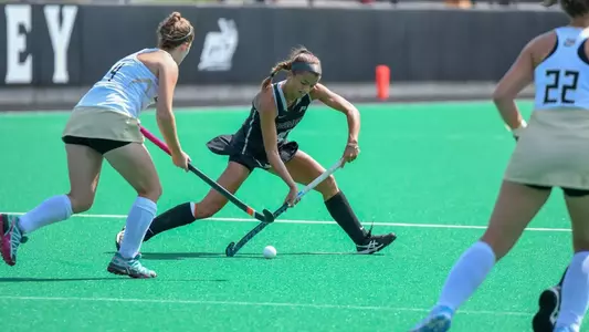 Field Hockey forward Izzy Mendez is pictured passing the ball in front of the circle while surrounded by two Bryant defenders during their matchup at Lennon Family Field.