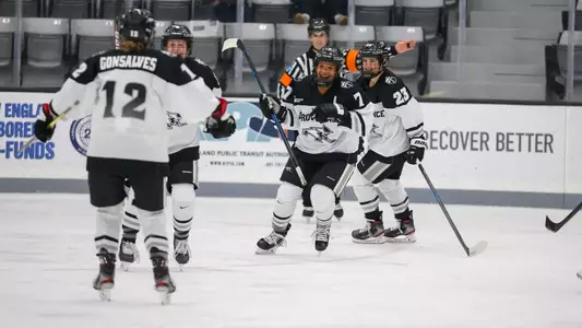Women's ice hockey players celebrating together after scoring a goal