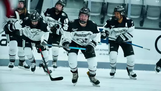 Women's ice hockey player Bailey Burton skating to the bench to celebrate with teammates after scoring a goal
