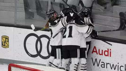 A photo of the women's ice hockey team celebrating together after scoring a goal during a game