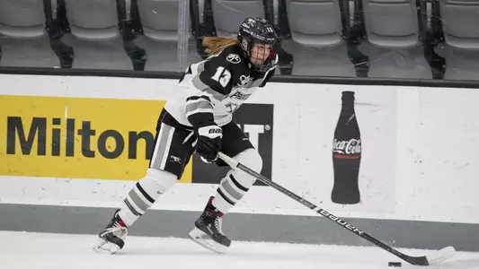 A photo of women's ice hockey player Emily Landry skating up the ice with the puck during a game