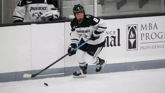 Women's ice hockey player Bailey Burton skating with the puck during a game