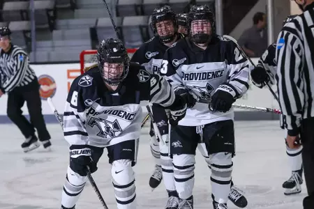 Women's Ice Hockey player Audrey Knapp skating towards the bench to celebrate with teammates after scoring a goal
