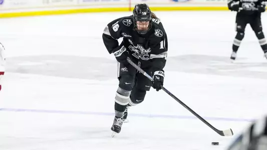 Women's Ice Hockey player Reichen Kirchmair skating with the puck in a game against Boston College