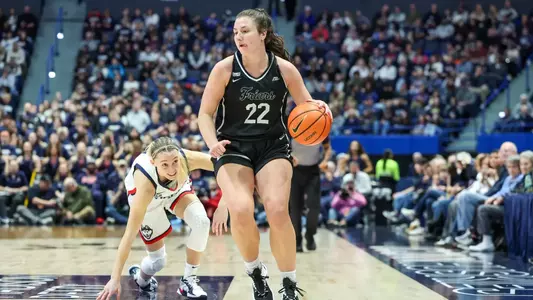 Brynn Farrell - women's basketball action photo vs. UConn dribbles away from Paige Bueckers