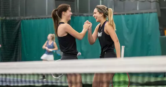 Tennis players Camila Barrera and Erika Beltran shake hands in celebration during an 2024 indoor doubles match.