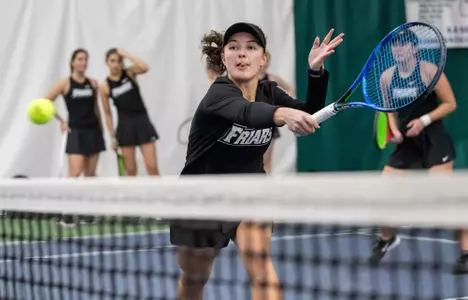 Tennis player Elisa Davalos goes for a backhand hit near the net during a 2024 indoor match.