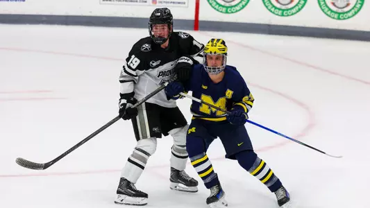 Men's Hockey's Tanner Adams in a battle against Michigan