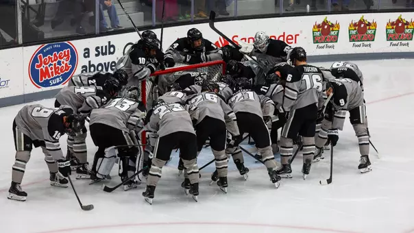 Men's Hockey team huddles around the goal prior to a game against UConn
