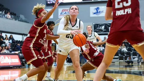 Ashley Dinges holding a basketball in between two Boston College defenders before going up for a shot.