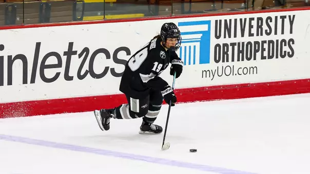 Women's ice hockey player Emma Hobauer skating with the puck during a game