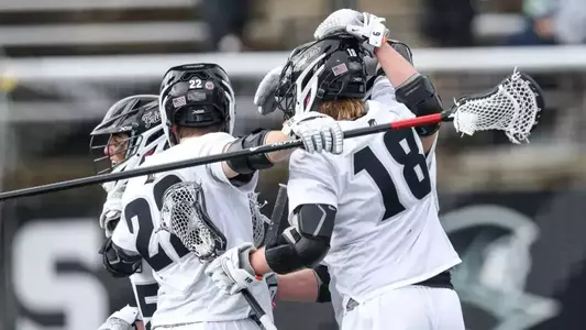Lacrosse players celebrate goal in a huddle versus Holy Cross.