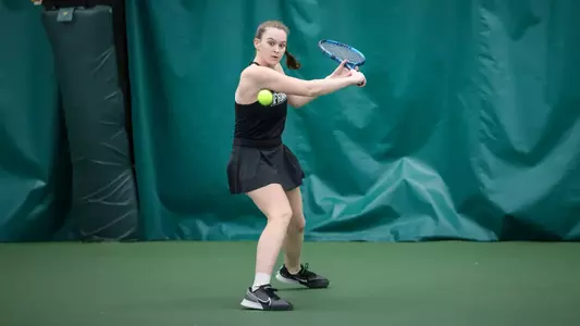 Tennis player Lauren Carson prepares to hit the ball backhand during an indoor match.