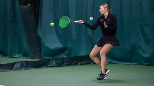 Tennis player Elise Leik hits the ball forehand during an indoor match.