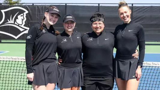 Tennis seniors Lauren Carson and Elisa Davalos, and Graduate Students Liria Loira and Elise Leik pose together on the court before a match.