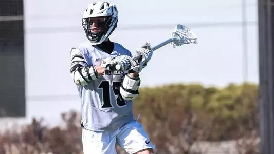 Men's Lacrosse player Ryan Bell passing the ball in a game against Loyola