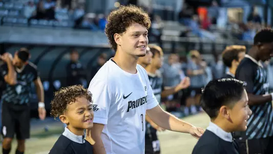 Fernando Garcia Gil walks out to field with youth player vs Bryant