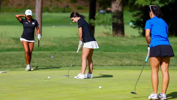 Women's golf player Olivia Arone hitting a putt into the cup
