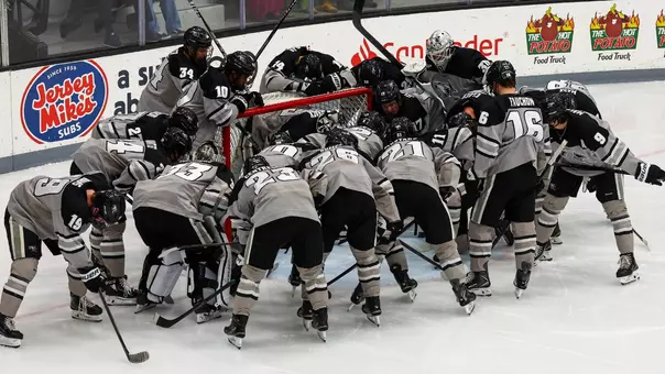Men's hockey team huddles up around the net prior to a game at Schneider Arena.