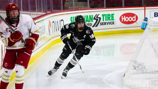 Women's ice hockey player Reichen Kirchmair skating after a puck during a game against Boston College
