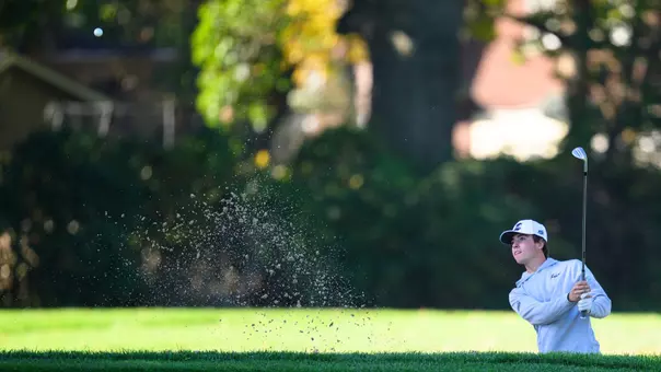Men's golfer Zac Georgantas hitting a bunker shot