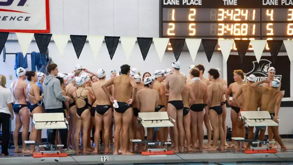 Swim and Diving team gathers on the pool deck near the starting blocks for a meeting.