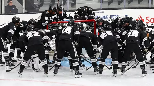 Men's Hockey Team Huddle around the net against Stonehill
