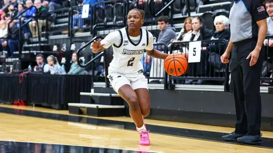 Princess Moody dribbles the ball near the sideline while looking for a teammate to pass to.