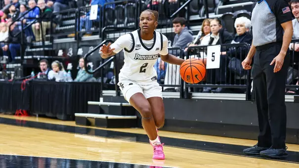 Princess Moody dribbles the ball near the sideline while looking for a teammate to pass to.