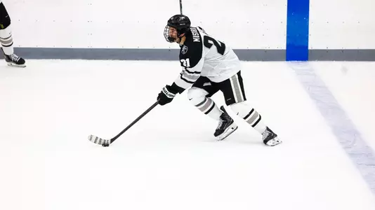 Men's Hockey's John Mustard carrying the puck at Schneider Arena